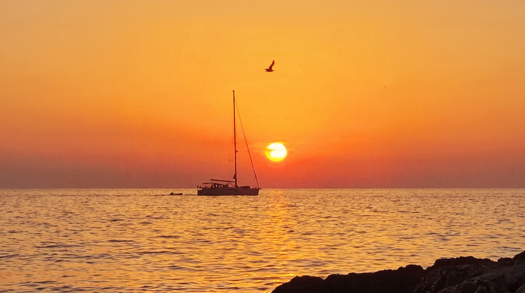 Velero recortado contra el sol en la puesta de sol del Mediterráneo